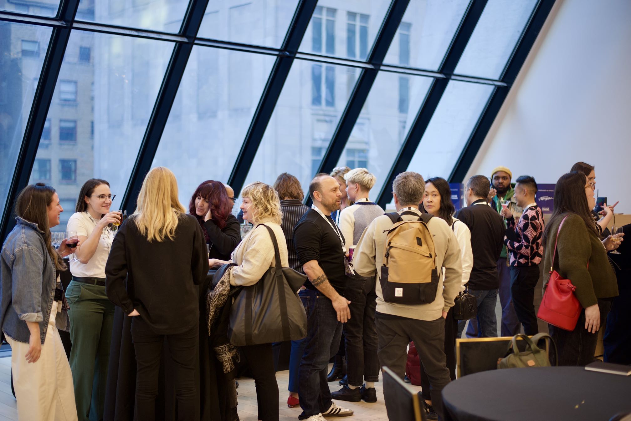 A crowd of smiling, chatting people sharing drinks at the end of the day.
